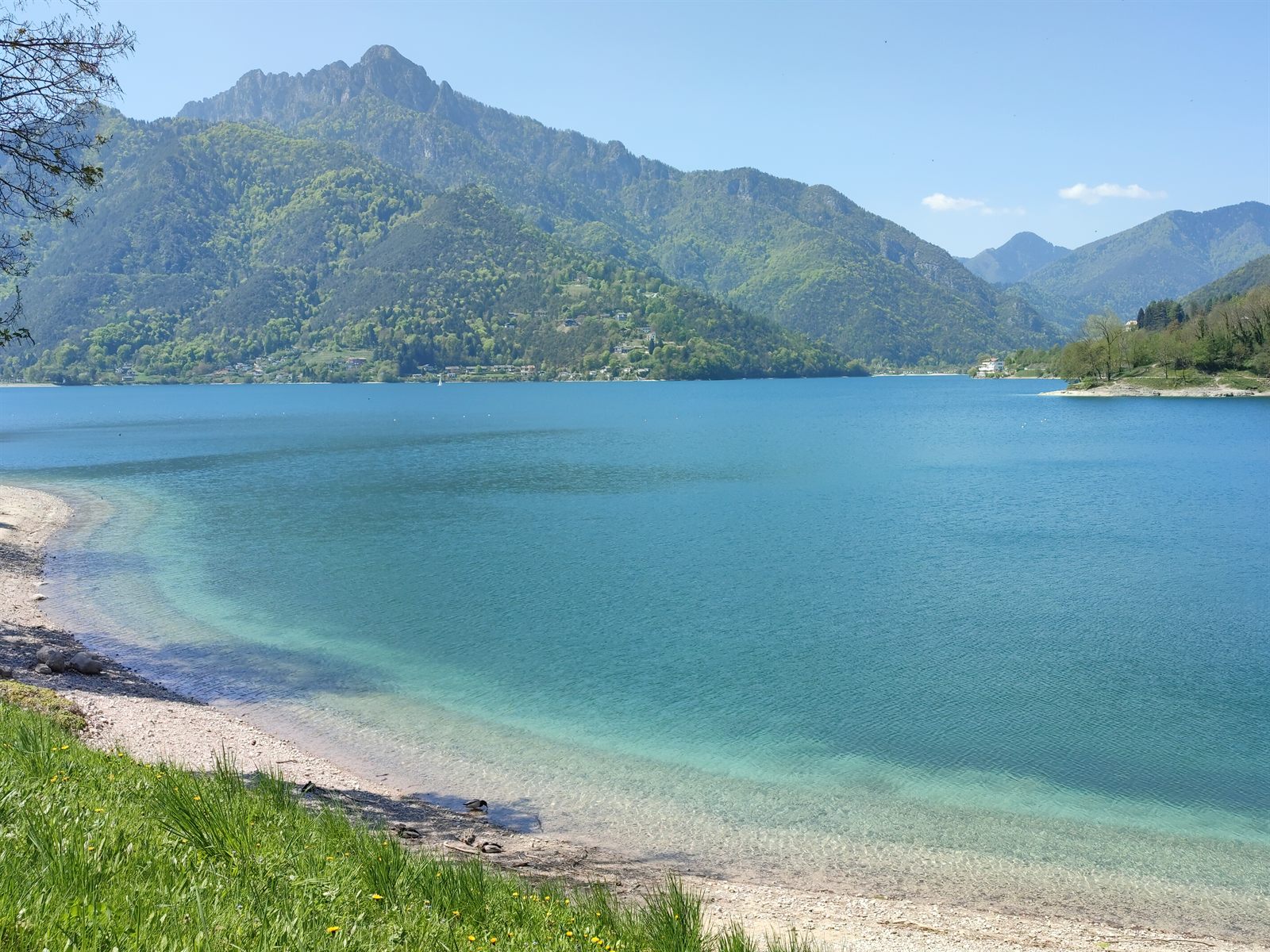 La spiaggia di ghiaia bianca del Lago di Ledro con l'acqua turchese e le montagne