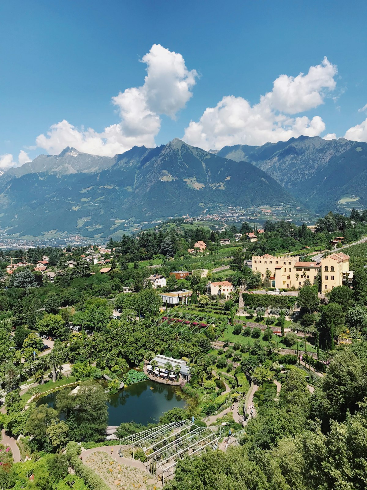 Giardini terrazzati con un laghetto e un edificio storico, con le montagne sullo sfondo