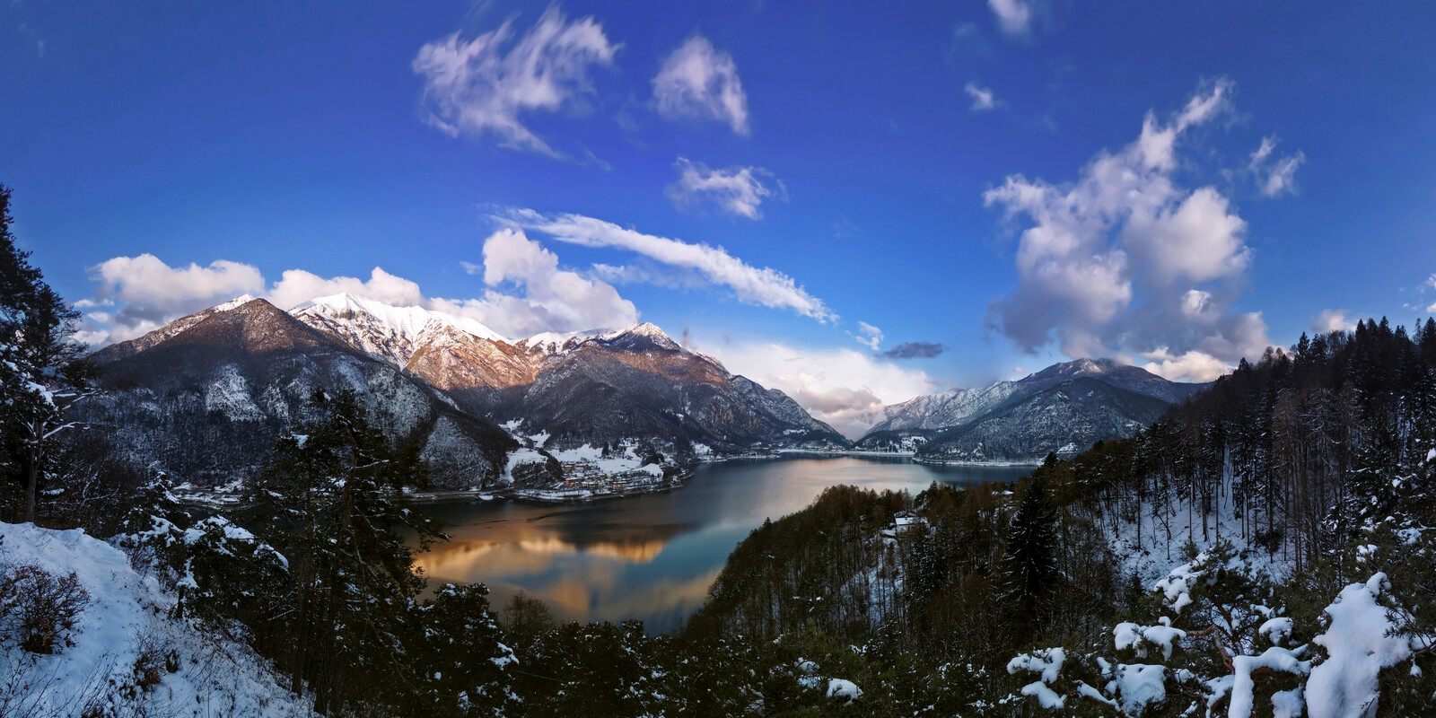 Panoramica invernale del Lago di Ledro con le montagne innevate e i paesi sulla riva